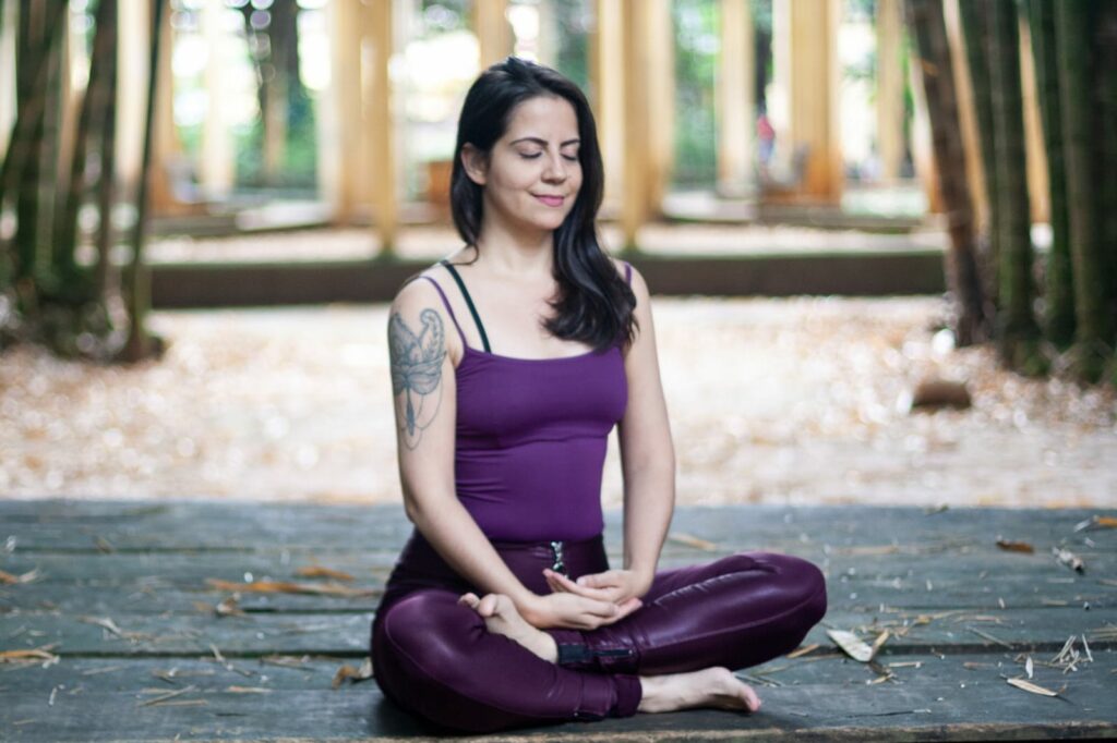 Thais Barbeiro, professora de SwáSthya Yôga desde 2006 em posição de meditação, com os olhos fechados e um leve ar de sorriso no semblante.